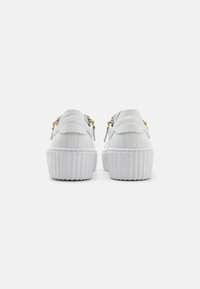 Weiße Leder-Sneaker mit einer strukturierten Oberfläche, ausgestattet mit einer geriffelten weißen Sohle und goldenen Akzenten an der Rückseite.