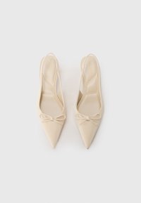 Beige pointed-toe slingback shoes with a smooth texture and bow detail at the front, featuring a slim heel and an open back design.