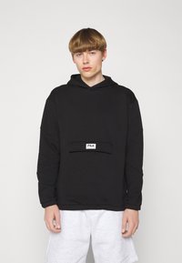 Felpa nera con cappuccio, caratterizzata da una tasca anteriore e un patch con il logo FILA bianco. Realizzata in tessuto morbido con una vestibilità comoda e spalle scese.
