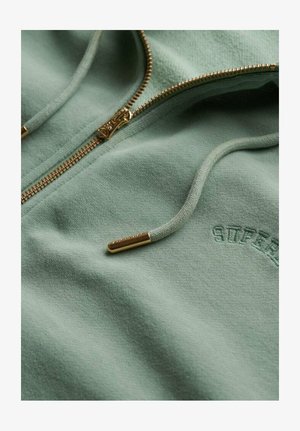 Sweatshirt zippé vert menthe en tissu doux, avec fermeture éclair dorée, logo brodé et cordon de serrage ajustable avec embouts dorés.