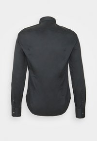 Svart långärmad skjorta med spetsig krage, knäppning vid ärmsluten och en mjuk yta. Har en skräddarsydd passform och en rundad nederkant baktill.