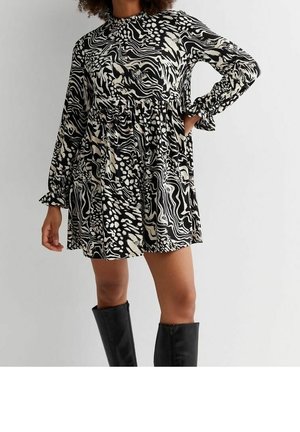 Sukienka w czarno-białe wzory z długim rękawem, z wysokim dekoltem, obniżoną talią i fakturowanym materiałem. W zestawie z czarnymi, wysokimi botkami do kolan.