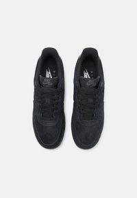 Paire de baskets noires Nike Air Force 1 vues de dessus avec des lacets visibles et des étiquettes de languette à la marque.