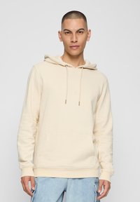 Crèmekleurige hoodie gemaakt van zachte stof, met een voorzak, verstelbare capuchon met trekkoord en geribbelde manchetten. Casual pasvorm.