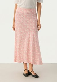 Lunga gonna rosa con un motivo floreale, realizzata in tessuto morbido. Presenta una vita adatta e fluisce dolcemente fino all'orlo. Abbinata a ballerine nere.