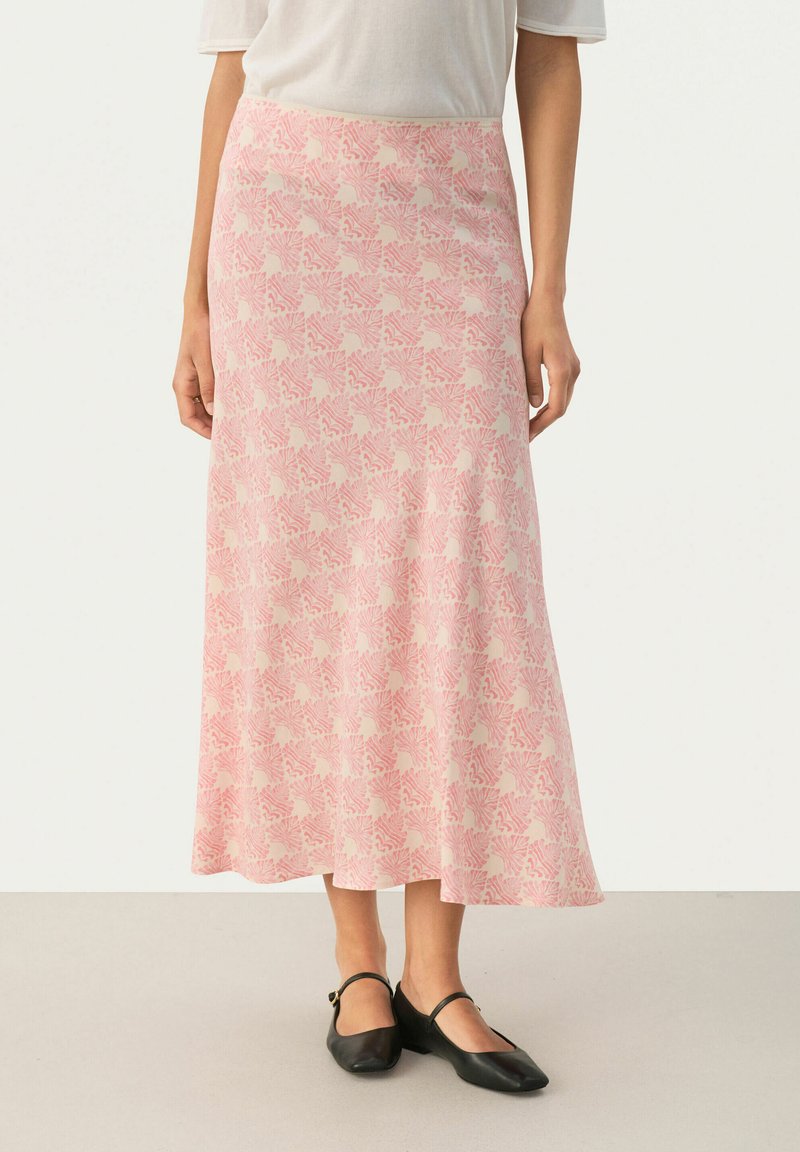 Lunga gonna rosa con un motivo floreale, realizzata in tessuto morbido. Presenta una vita adatta e fluisce dolcemente fino all'orlo. Abbinata a ballerine nere.