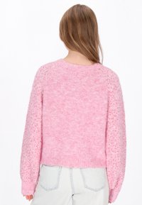 Suéter rosa y esponjoso con cuello redondo y mangas abullonadas texturizadas. Presenta un material de punto suave y un diseño corto.