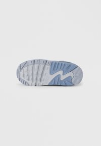 Nike obutev z zunanjim delom v svetlo modri in sivi barvi, ki ima teksturirano gumijasto površino z obliko zareze in izpostavljenim logotipom.