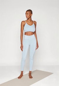 Šviesiai mėlynas sportinis kostiumas, susidedantis iš trumpų ilgų švarkelių ir aukštakulnių tamprių tamprių, pagamintas iš lygios, tamprios medžiagos su minimaliais siūlais.