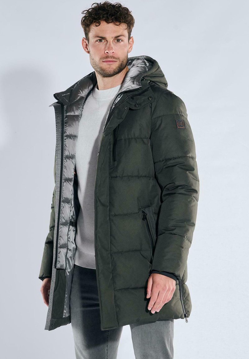 Green padded coat with a hood, featuring a gray interior lining, side zip pockets, and a logo patch on the sleeve.