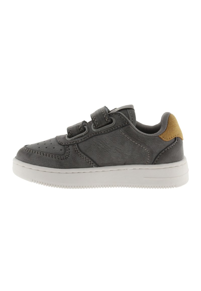 Zapatillas sintéticas grises con correas de Velcro, puntera redondeada, parte superior texturizada y acento de talón en tono marrón. Suela de goma con patrón de agarre.