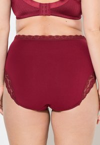 Bordeaux hoge taille ondergoed van een gladde stof, met een kanten inzet aan de zijkanten en een gegolfde tailleband.