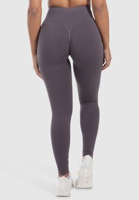 Leggings a vita alta e elasticizzati in grigio scuro con una texture liscia e dettagli di contorno. Presentano una gamba affusolata e un cintura elastica.