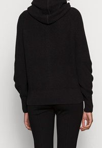 Czarna dziana bluza z kapturem o prążkowanej fakturze, dużym kapturze i opuszczonych ramionach. Posiada prosty dół i dopasowane mankiety.