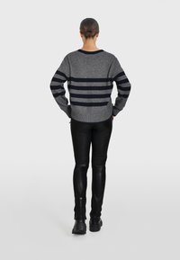 Maglione grigio a righe con strisce orizzontali blu navy, con ampi polsini a coste e orlo. Abbinato a pantaloni in pelle nera aderenti e stivali neri robusti.