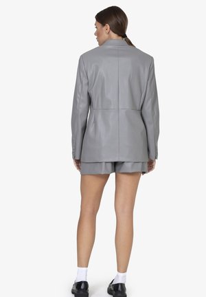 Grijze neplederen blazer met een gestructureerde silhouet, gecentreerde naad en knoopdetails, gecombineerd met bijpassende shorts. Soepele textuur.