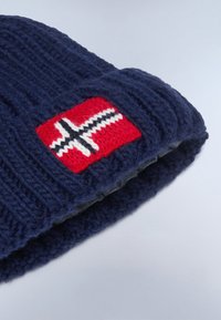 Navy blue knitted winter hat with a red patch featuring a white and black Nordic cross design on it.