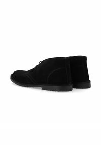 Bottines en suede noir avec une texture lisse, bout arrondi, couture minimale et semelle en caoutchouc plate. Les lacets sont visibles à l'avant.