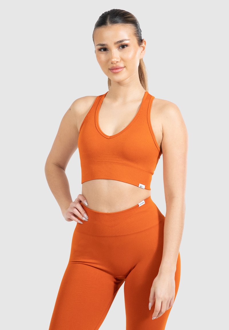 Conjunto de top corto y mallas en tela de canalé naranja. Incluye un escote en V, etiqueta con el logo y un diseño de cintura alta para un look ajustado.
