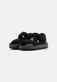 Svart sandaler med kryssede stropper og åpen tådesign. Laget av mykt materiale med teksturert såle og justerbar borrelås-lukking.