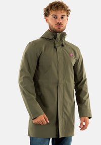 Veste imperméable vert olive avec une fermeture éclair devant, capuche ajustable et patch logo. Dispose de poches latérales et d'une coupe droite.