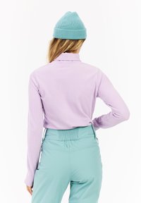 Haut à manches longues côtelé lavande avec un col montant, associé à un pantalon vert menthe avec une taille froncée et des poches latérales.
