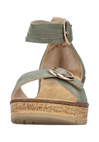 Sandalo verde in suede con cinturino alla caviglia, fibbia circolare dorata, punta aperta e suola in sughero decorata. Soletta piatta per il massimo comfort.