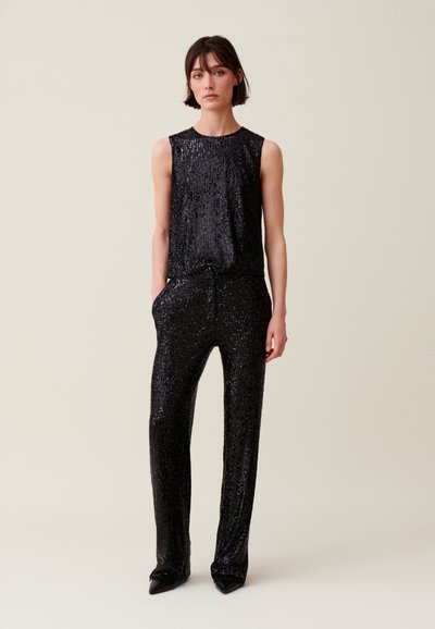Mono de lentejuelas negras con diseño sin mangas, escote redondo y pantalones ajustados. Cuenta con bolsillos y un cordón en la cintura.