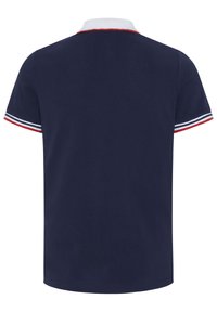 Marineblaues Poloshirt mit weißem Kragen und rotem Besatz. Die kurzen Ärmel sind mit navyblauen, roten und weißen Streifen gestaltet. Aus einem Baumwollgemisch mit glatter Textur.