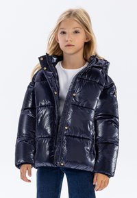 Giacca puffa blu navy con finitura lucida, chiusura con zip e bottoni a scatto dorati. Presenta un cappuccio e una texture imbottita per il calore.
