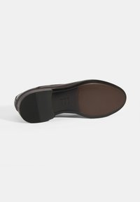 Semelle de chaussure en cuir marron avec une forme lisse et arrondie ; présente un talon en caoutchouc noir texturé et un logo de marque en relief.