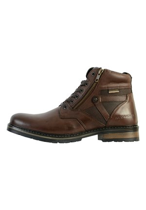Botte en cuir brun avec un bout arrondi, un laçage à l'avant, une fermeture éclair sur le côté et des accents en maille nylon. Semelle en caoutchouc robuste et talon texturé.