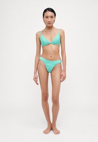 Lys tyrkisk ribbet bikini-sett med trekantet topp med tynne stropper og matchende høy-kuttet bunn. Myk tekstur, minimalistisk design.