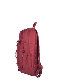 Red fabric backpack with multiple zipper compartments, mesh side pockets, and adjustable straps. It has a padded back for comfort.