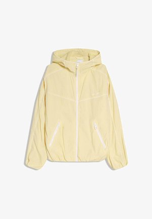 Lichtgele gewatteerde jas met capuchon, witte rits en twee schuin geplaatste zakken met rits, voorzien van witte biezen op mouwen en borst.