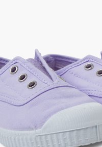 Purple canvas slip-on shoes with white rubber soles and eyelets, featuring a textured surface and rounded toe design.