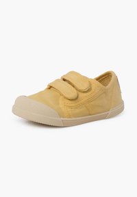 Žlutá plátěná bota s dvěma suchými zipy, kulatou špičkou, gumovou podrážkou a prošívanými detaily. Hladký povrch a minimalistický design.