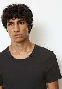 T-shirt noir en coton à col rond, avec des manches courtes, pr�ésentant une texture lisse et un léger stretch. S'ajuste près du corps.