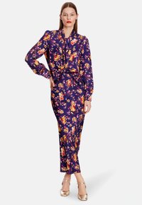 Purple floral dress with long sleeves and a tie neck, featuring a fitted silhouette and vibrant flower patterns on smooth fabric.