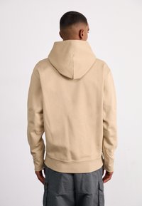 Felpa beige con collo alto e cappuccio regolabile. Caratterizzata da maniche lunghe, polsini a coste e vestibilità rilassata. Design semplice, texture morbida.
