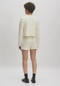 Bureauauwt lichtcrème textuurtrui gecombineerd met bijpassende hooggetailleerde shorts, met korte mouwen en een relaxte fit.