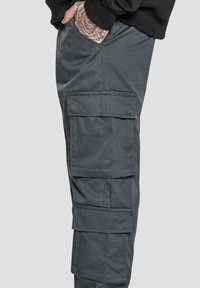 Grå cargo bukser med flere store lommer, en rett snitt og en glatt tekstur. Detaljer om sidelommene er synlige på bena.