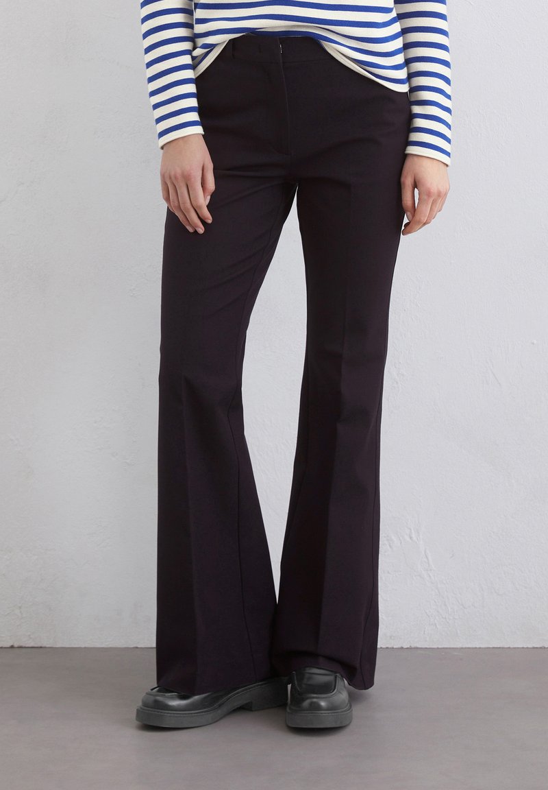 Czarne spodnie flare o gładkiej fakturze i dopasowanej talii, zestawione z niebieską i białą pasiastą bluzką z długim rękawem.