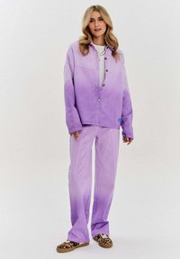 Fialový gradientový oversized kabát s odpovídajícími širokými kalhotami. Měkká tkanina, zapínání na knoflík a boční švy, spárované s leopardími botami.