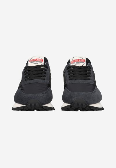Schwarze Sportschuhe mit einer Kombination aus glattem Stoff und Wildledertexturen, mit einer weißen Sohle und einem Markenetikett auf der Zunge.