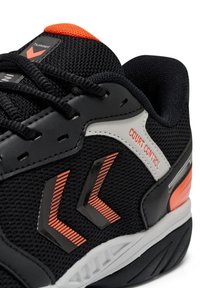 Scarpa sportiva nera realizzata con materiali in rete e sintetici, con dettagli arancioni, una punta decorata e un'etichetta "Court Control" sul lato.
