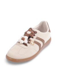 Baskets en suède blanc avec des rayures marron et des embellissements floraux. Présentent des fleurs texturées et un charme décoratif en forme de soleil sur les lacets.