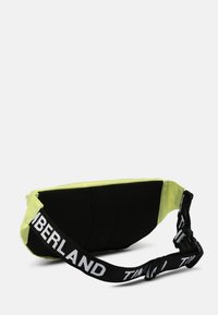 Borsone giallo e nero con schienale imbottito e tracolla nera regolabile, con la scritta "TIMBERLAND" in bianco.
