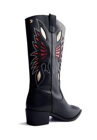 Bota de cowboy de cuero negro con patrones de costura en llamas rojos, blancos y naranjas en el caña y un tacón bajo apilado.