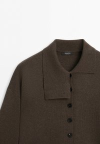 Brun stickad cardigan med stor krage och svarta knappar på framsidan, uppvisad platt mot en vit bakgrund.